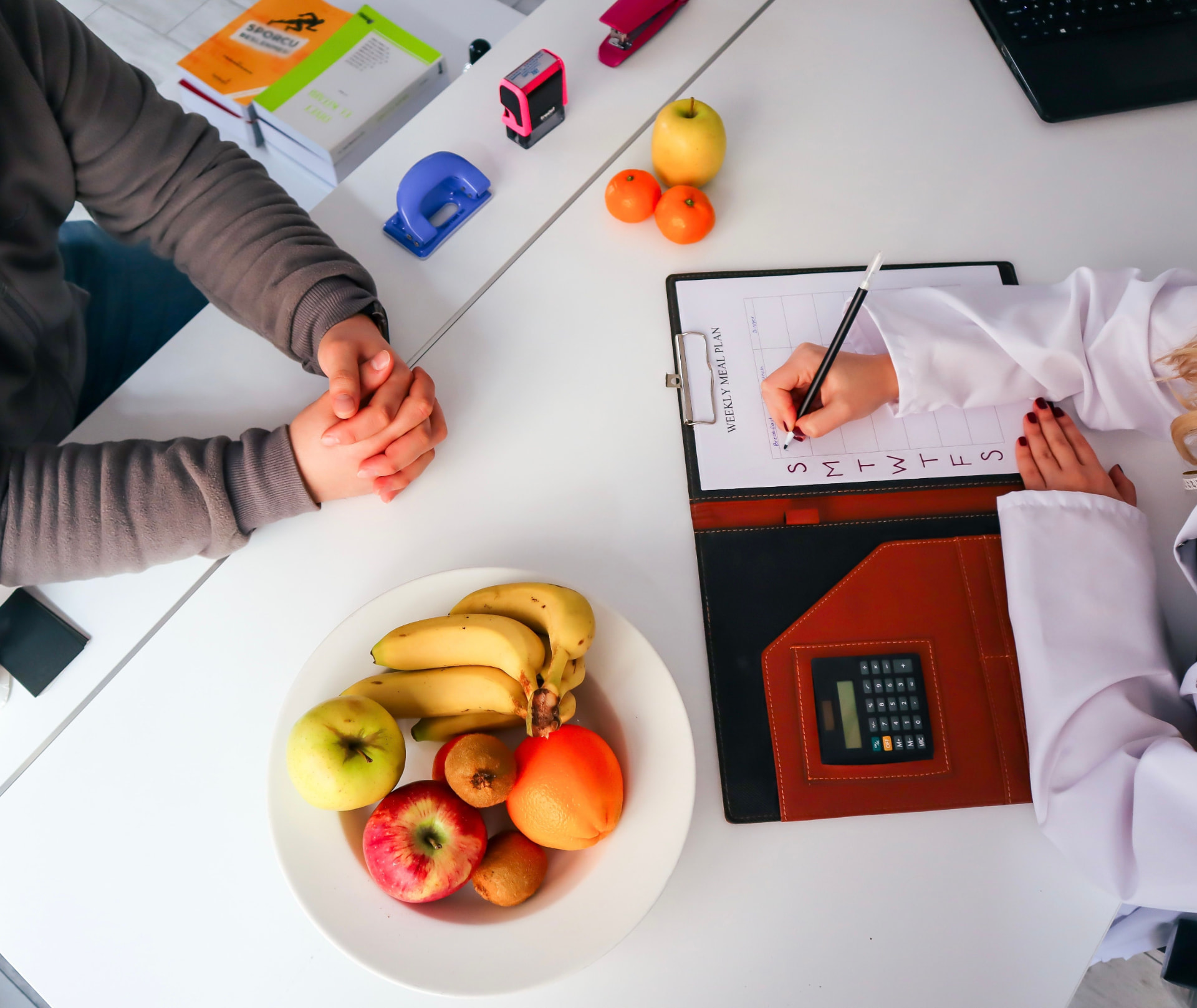Ernährungsberatung: Wochenplan wird gemeinsam am Tisch mit Obst besprochen